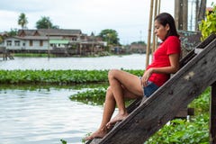 Женщина сидя на деревянной воде лестниц стоковая фотография Женщина сидя на деревянной воде лестниц стоковая фотография