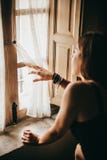 Женщина смотря любопытно через окно в темноте стоковое фото Женщина смотря любопытно через окно в темноте стоковое фото