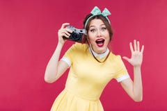 Жизнерадостная девушка pinup используя винтажную камеру и фотографирующ стоковые изображения Жизнерадостная девушка pinup используя винтажную камеру и фотографирующ стоковые изображения
