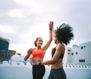 Жизнерадостные женщины фитнеса давая высокие 5 пока jogging на крыше стоковые фото Жизнерадостные женщины фитнеса давая высокие 5 пока jogging на крыше стоковые фото