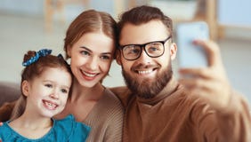 Жизнерадостные счастливые отец и ребенок матери семьи принимают selfies, фотографируют стоковое изображение Жизнерадостные счастливые отец и ребенок матери семьи принимают selfies, фотографируют стоковое изображение