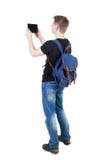 Задний взгляд стоять молодой человек с планшетом и backpac стоковое изображение rf Задний взгляд стоять молодой человек с планшетом и backpac стоковое изображение rf