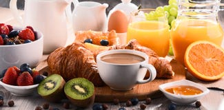 Завтрак служил с кофе, соком, круассанами и плодоовощами стоковое фото rf Завтрак служил с кофе, соком, круассанами и плодоовощами стоковое фото rf