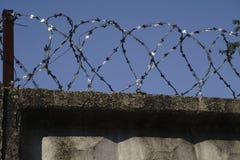 Загородка колючей проволоки прикрепленная вокруг стен тюрьмы стоковые фото Загородка колючей проволоки прикрепленная вокруг стен тюрьмы стоковые фото