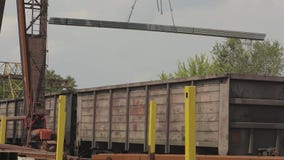 Загрузка трубы профиля краном на козлах в товарный вагон, металл нагрузок в складе, большом кране на козлах Загрузка трубы профиля краном на козлах в товарный вагон, металл нагрузок в складе, большом кране на козлах