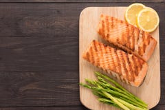 Зажаренные семги и лимон, спаржа на деревянной предпосылке стоковое фото rf Зажаренные семги и лимон, спаржа на деревянной предпосылке стоковое фото rf