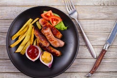 Зажаренные сосиски с фраями Сосиски с картошками и овощами Стоковое фото RF Зажаренные сосиски с фраями Сосиски с картошками и овощами Стоковое фото RF