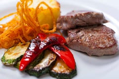 Зажаренные стейки свинины с картошками, перцами и цукини стоковая фотография Зажаренные стейки свинины с картошками, перцами и цукини стоковая фотография