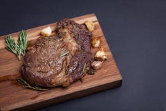 Зажаренный стейк ribeye мраморной говядины с специями на деревянной доске С космосом экземпляра стоковая фотография rf Зажаренный стейк ribeye мраморной говядины с специями на деревянной доске С космосом экземпляра стоковая фотография rf