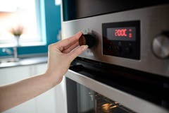 Закройте вверх контроля температуры установки руки женщины на печи стоковые фотографии rf Закройте вверх контроля температуры установки руки женщины на печи стоковые фотографии rf