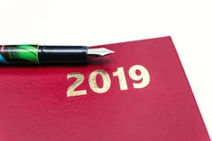 Закройте вверх красного кожаного дневника 2019 с авторучкой на белой предпосылке стоковая фотография Закройте вверх красного кожаного дневника 2019 с авторучкой на белой предпосылке стоковая фотография