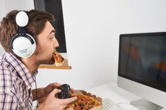 Закройте вверх молодого симпатичного небритого человека с короткими волосами в вскользь рубашке играя компютерные игры с регулято стоковое фото rf Закройте вверх молодого симпатичного небритого человека с короткими волосами в вскользь рубашке играя компютерные игры с регулято стоковое фото rf