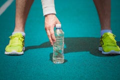 Закройте вверх мужского jogger держа пластичную бутылку воды на runni стоковые изображения rf Закройте вверх мужского jogger держа пластичную бутылку воды на runni стоковые изображения rf
