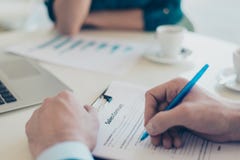 Закройте вверх по накладным расходам над фото верхней части рук ` s человека подписывая жулика специалиста по набору персонала аг стоковое фото Закройте вверх по накладным расходам над фото верхней части рук ` s человека подписывая жулика специалиста по набору персонала аг стоковое фото