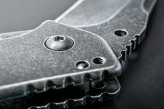 Закройте вверх половинного открытого черного складывая ножа на темной земле Стоковое Фото Закройте вверх половинного открытого черного складывая ножа на темной земле Стоковое Фото