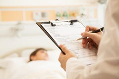 Закройте вверх сочинительства доктора на медицинской диаграмме при пациент лежа в больничной койке на заднем плане Стоковое Фото Закройте вверх сочинительства доктора на медицинской диаграмме при пациент лежа в больничной койке на заднем плане Стоковое Фото