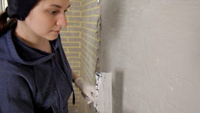 Замазка маленькой девочки, затир на стене, и после этого выравнивает замазку на стене с его рукой Ремонт, ровные стены сток-видео Замазка маленькой девочки, затир на стене, и после этого выравнивает замазку на стене с его рукой Ремонт, ровные стены сток-видео