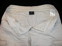 Замыкает накоротко бежевое, лицевая сторона unbuttoned, с ярлыками, на черной предпосылке стоковое изображение rf Замыкает накоротко бежевое, лицевая сторона unbuttoned, с ярлыками, на черной предпосылке стоковое изображение rf