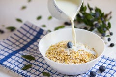 Здоровая овсяная каша с голубиками, молоко завтрака льет от кувшина молока к каше на светлой предпосылке стоковые фото Здоровая овсяная каша с голубиками, молоко завтрака льет от кувшина молока к каше на светлой предпосылке стоковые фото