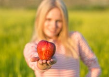Здоровая привлекательная женщина eatiing красное яблоко лето поля зеленое стоковая фотография Здоровая привлекательная женщина eatiing красное яблоко лето поля зеленое стоковая фотография