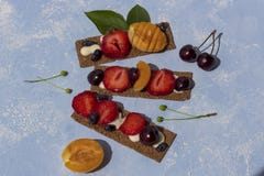 Здоровые и вкусные тосты с сыром, плодами и ягодами творога на голубой предпосылке стоковые изображения Здоровые и вкусные тосты с сыром, плодами и ягодами творога на голубой предпосылке стоковые изображения