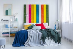 Зеленые и голубые одеяла на белой кровати с bedhead в белом, интерьером радуги спальни scandi Реальное фото стоковые фотографии rf Зеленые и голубые одеяла на белой кровати с bedhead в белом, интерьером радуги спальни scandi Реальное фото стоковые фотографии rf