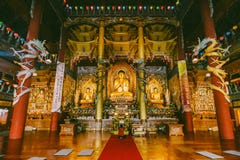 Золотые статуи Будды внутри виска Yakcheonsa Jeju, Южная Корея стоковая фотография rf Золотые статуи Будды внутри виска Yakcheonsa Jeju, Южная Корея стоковая фотография rf