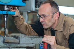 Зрелый человек используя сверля машину на промышленной фабрике стоковые фотографии rf Зрелый человек используя сверля машину на промышленной фабрике стоковые фотографии rf