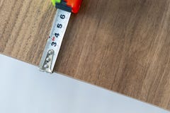 Измерять деревянный стол с зеленой и оранжевой покрашенной рулеткой стоковое изображение rf Измерять деревянный стол с зеленой и оранжевой покрашенной рулеткой стоковое изображение rf