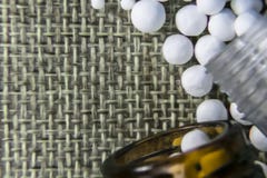 Изображение близкого взгляда гомеопатической медицины состоя из таблеток и бутылок медицины на предпосылке джута стоковая фотография rf Изображение близкого взгляда гомеопатической медицины состоя из таблеток и бутылок медицины на предпосылке джута стоковая фотография rf