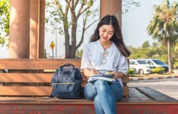 Изображение изумительной красивой женщины сидя на стенде в книге чтения парка стоковые изображения rf Изображение изумительной красивой женщины сидя на стенде в книге чтения парка стоковые изображения rf