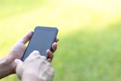 Изображение конца-вверх мужских рук используя черный смартфон в парке, человеке стоковые изображения Изображение конца-вверх мужских рук используя черный смартфон в парке, человеке стоковые изображения