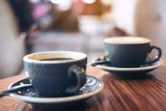 Изображение крупного плана 2 голубых чашек горячего кофе latte и кофе Americano на винтажном деревянном столе Стоковая Фотография RF Изображение крупного плана 2 голубых чашек горячего кофе latte и кофе Americano на винтажном деревянном столе Стоковая Фотография RF