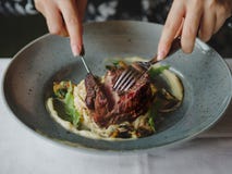 Изображение макроса вкусного блюда в голубой плите на белой предпосылке таблицы Рука режет часть сочного мяса экземпляр стоковое изображение rf Изображение макроса вкусного блюда в голубой плите на белой предпосылке таблицы Рука режет часть сочного мяса экземпляр стоковое изображение rf