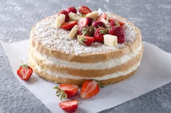 Изумительно очень вкусный торт губки и целый, куски клубник на печь бумаге, серой поверхности стоковые изображения rf Изумительно очень вкусный торт губки и целый, куски клубник на печь бумаге, серой поверхности стоковые изображения rf