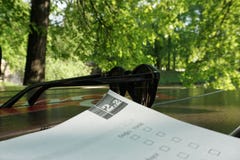 Изучающ с книгой в парке, солнечные очки на таблице стоковые изображения Изучающ с книгой в парке, солнечные очки на таблице стоковые изображения