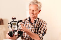 Испуская лучи старший инженер gazing на новой робототехнической машине стоковая фотография rf Испуская лучи старший инженер gazing на новой робототехнической машине стоковая фотография rf