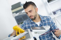 Испытание техника более phoocopier используя вольтамперомметр стоковая фотография Испытание техника более phoocopier используя вольтамперомметр стоковая фотография