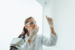 Исследовательская лабаратория ученого в безопасных стеклах используя микроскоп для анализировать анти- бактерии через стекло скол стоковое изображение Исследовательская лабаратория ученого в безопасных стеклах используя микроскоп для анализировать анти- бактерии через стекло скол стоковое изображение