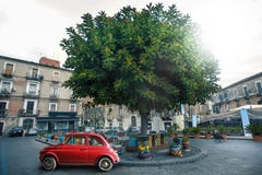 Итальянский старый красный автомобиль припарковал около дерева в квадрате в городе Катании в Италии стоковое изображение Итальянский старый красный автомобиль припарковал около дерева в квадрате в городе Катании в Италии стоковое изображение