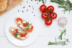 Итальянские тосты bruschetta с томатами и сыром на белой деревянной предпосылке, взгляде сверху стоковая фотография Итальянские тосты bruschetta с томатами и сыром на белой деревянной предпосылке, взгляде сверху стоковая фотография