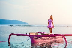 Кавказская девушка представляя положение на розовой шлюпке в море на заходе солнца на острове Gili стоковые фото Кавказская девушка представляя положение на розовой шлюпке в море на заходе солнца на острове Gili стоковые фото