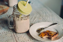 Какао с молоком в опарнике и тостах на кухонном столе стоковое изображение Какао с молоком в опарнике и тостах на кухонном столе стоковое изображение