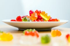 Камедеобразные медведи на белых плите и деревянном столе стоковая фотография Камедеобразные медведи на белых плите и деревянном столе стоковая фотография