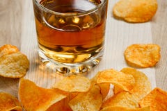 Картофельные стружки и стекло яблочного сока на деревянном столе картофельные стружки и стекло вискиа стоковые фотографии rf Картофельные стружки и стекло яблочного сока на деревянном столе картофельные стружки и стекло вискиа стоковые фотографии rf