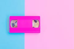 Кассета VHS на мягком пинке и голубой бумажной предпосылке Минимальная концепция принципиальная схема творческая Концепция кино И стоковое фото rf Кассета VHS на мягком пинке и голубой бумажной предпосылке Минимальная концепция принципиальная схема творческая Концепция кино И стоковое фото rf