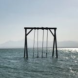 Качание деревянных детей стоит в голубом штиле на море под открытым чистым небом стоковое фото rf Качание деревянных детей стоит в голубом штиле на море под открытым чистым небом стоковое фото rf