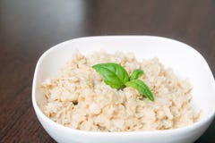 Каша овсяной каши/овсы/хлопья для завтрака каши украшенные с зелеными листьями на деревянном столе Здоровая еда, еда завтрака стоковые фото Каша овсяной каши/овсы/хлопья для завтрака каши украшенные с зелеными листьями на деревянном столе Здоровая еда, еда завтрака стоковые фото
