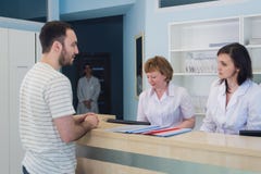 Квалифицированные усмехаясь доктора работая с клиентом на приемной в больнице стоковое фото Квалифицированные усмехаясь доктора работая с клиентом на приемной в больнице стоковое фото