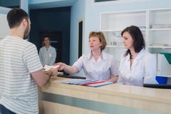 Квалифицированные усмехаясь доктора работая с клиентом на приемной в больнице стоковые изображения rf Квалифицированные усмехаясь доктора работая с клиентом на приемной в больнице стоковые изображения rf